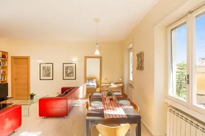 a living room with a table and a red couch at Trastevere Garden by Rental in Rome in Rome