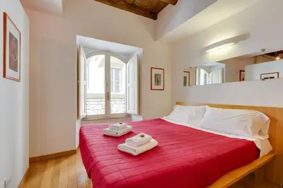 a bedroom with a red bed with two towels on it at Barberini 360 in Rome