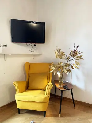 a yellow chair and a table with a tv on a wall at Historical Central Rome Flat in Rome