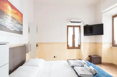 a bedroom with a white bed and a flat screen tv at Elegant & Quiet Apartment next to Colosseo in Rome
