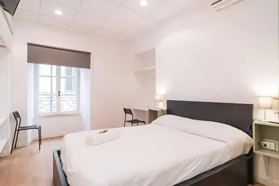 a white bedroom with a large bed and a table at Trevi's BuddyRent in Rome