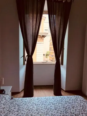 a bedroom with a bed and a window with curtains at White King Rooms in Rome