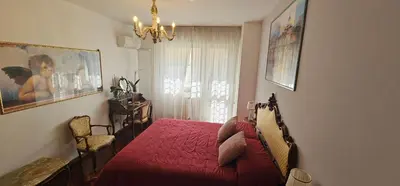 a bedroom with a red bed and a chandelier at Stanza classica Eur Tintoretto in Rome