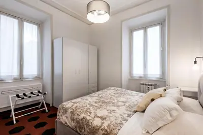 a bedroom with a bed with white walls and windows at Piazza Testaccio Home apt E1- Luminoso con vista piazza Testaccio in Rome