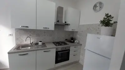 a kitchen with white cabinets and a sink and a refrigerator at FaMaCrì Home in Rome