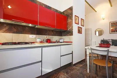 a kitchen with white counters and red cabinets at Cornelia - Charme Apartment in Rome