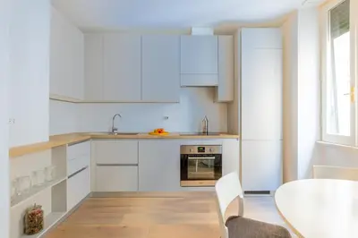 a kitchen with white cabinets and a table at Urban Chic 2 BR Vatican Escape in Rome