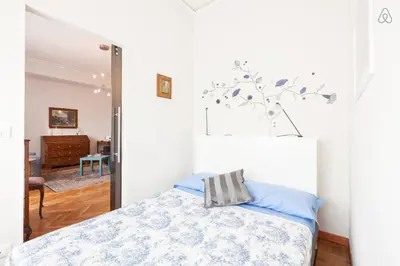 a bedroom with a bed with blue sheets and a tree on the wall at Charming Apartment Piazza del Popolo in Rome