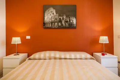 a bedroom with orange walls and a bed with two lamps at Vatican Rooms Holiday in Rome in Rome
