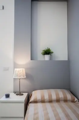 a bedroom with a bed and a table with a lamp at Vatican Rooms Holiday in Rome in Rome