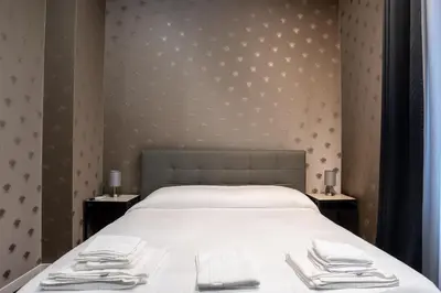a bedroom with a bed with white sheets and towels at SABA SUITE ROMA in Rome
