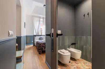 a bathroom with a toilet and a sink and a bed at Vatican Night Suites in Rome