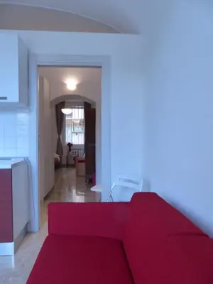 a living room with a red couch and a kitchen at Between Termini & Colosseo in Rome