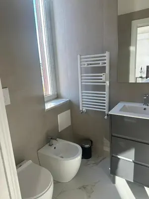 a white bathroom with a toilet and a sink at Maison Merulana Colosseo in Rome