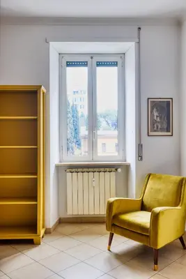 a living room with a yellow chair and a window at Yellow Stripes Apartment - San Giovanni by RHR in Rome