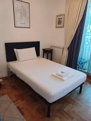 a bedroom with a bed with white sheets and two towels at Marcus Modern Apartment in Rome
