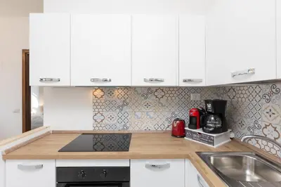 a kitchen with white cabinets and a sink at Laterano View by Rental in Rome in Rome