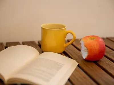 an open book and an apple on a wooden table at Room In Roma Isole in Rome