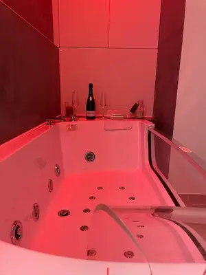 a bathroom with a tub with a bottle and two wine glasses at San Pietro love Apartament in Rome