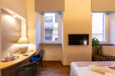 a hotel room with a bed and a desk and a tv at Fontana di Trevi Roma Luxury Suite in Rome