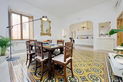 a dining room with a table and chairs on a rug at TreasureRome Opera & Trevi Grand Suite 3BR in Rome