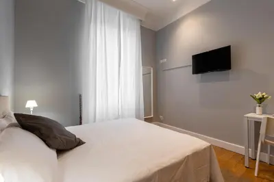 a bedroom with a white bed and a flat screen tv at River61 - Guest House in Rome