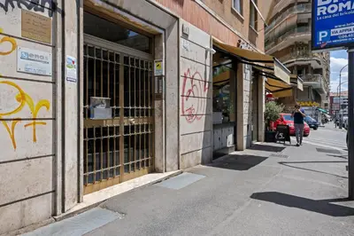 a woman walking down a sidewalk in front of a building at 543 Appia Avenue - Metro A by RHR in Rome