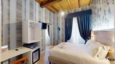 a bedroom with a large white bed and blue curtains at ROME'S GLORIA HOTEL in Rome