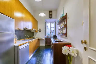 a large kitchen with wooden cabinets and a vase of flowers at Vespasiano Luxury apartment for 4 in Rome