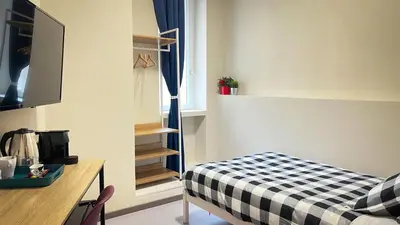a small room with a bed and a desk and a television at Ele rooms San Pietro in Rome