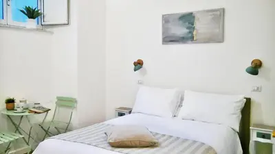 a white bedroom with a bed with white pillows at Vera Roma Suite&Apartment - Charming 3 bedroom apt - 20min walk from Colosseum in Rome