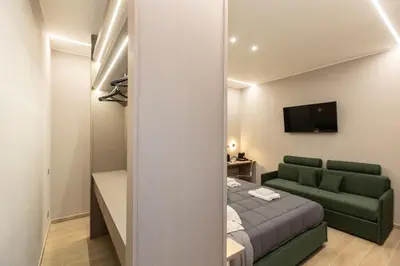 a bedroom with a bed and a couch and a television at IRON Luxury Rooms in Rome