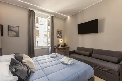 a bedroom with a bed and a couch and a television at IRON Luxury Rooms in Rome
