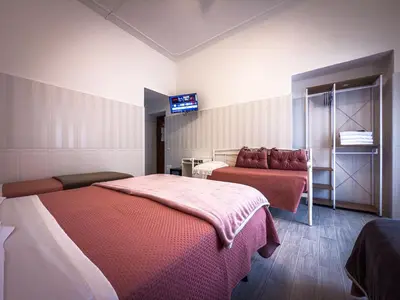 a bedroom with two beds and a tv on the wall at Hotel Giada Roma in Rome