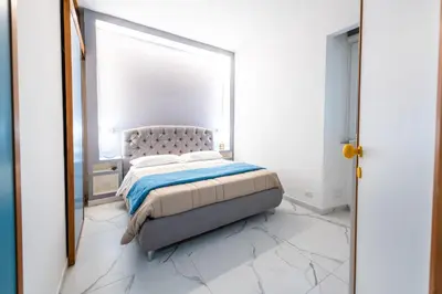 a white bedroom with a bed and a mirror at Casa Cate in Rome