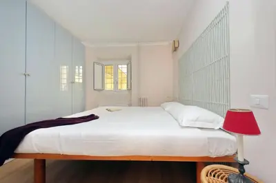 a white bedroom with a bed and a red lamp at Monti Studio in Rome