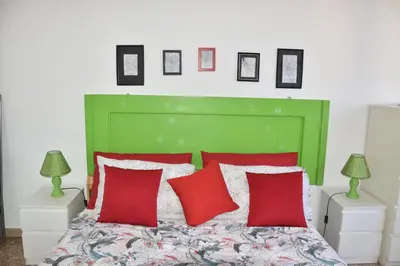 a green bed with red pillows in a bedroom at Aura Home Grazioso Appartamento a Pochi Passi dalla Metro A e C in Rome