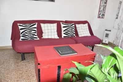 a living room with a red couch with pillows and a table at Aura Home Grazioso Appartamento a Pochi Passi dalla Metro A e C in Rome