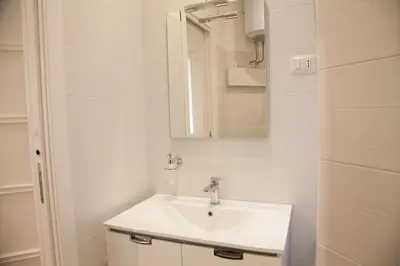 a white bathroom with a sink and a mirror at Cicerone 60 in Rome