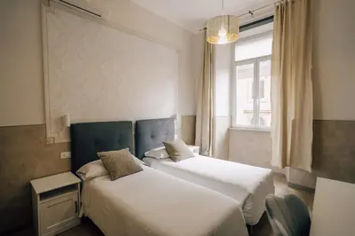 two beds in a room with a window at Mirabilia House in Rome