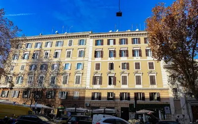 a large yellow building with cars parked in front of it at Blue Vatican House in Rome