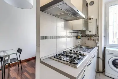 a white kitchen with a stove and a sink at Re di Roma Lovely Apartments in Rome