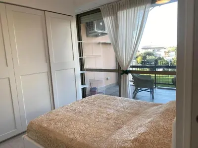 a bedroom with a bed and a view of a balcony at GREEN HOUSE - PARCO TIRRENO by Ohana in Rome