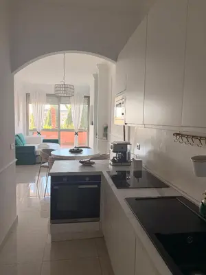 a kitchen with white cabinets and a living room at GREEN HOUSE - PARCO TIRRENO by Ohana in Rome