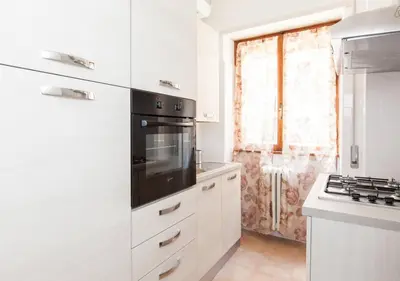 a kitchen with white cabinets and a black appliance at Navona Home in Rome