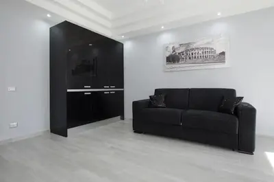 a living room with a black couch in a white room at Suite Noir St Peter View in Rome