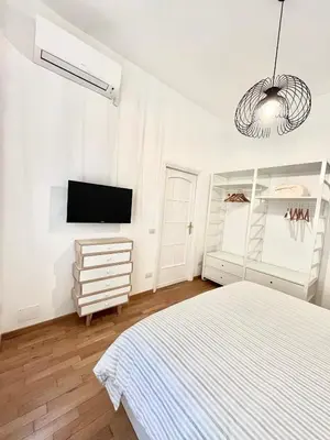 a white bedroom with a bed and a tv at Civitas Leonina Apartment in Rome