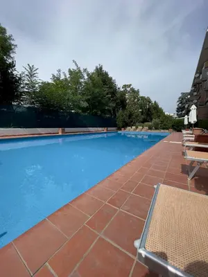 a large swimming pool with blue water and chairs at Sweet RHome - A due passi da San Pietro in Rome