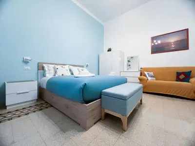 a bedroom with a blue bed and a couch at A casa di Ala in Rome