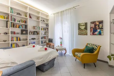 a bedroom with a large bed and a chair and bookshelves at Gianicolo Holiday House in Rome